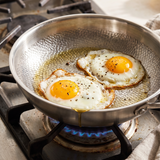Castmoor stainless steel frying pan cooking eggs on a gas stove